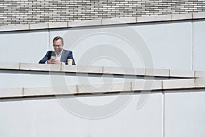 Mature Businessman Using Mobile Phone Standing Outside Office Building