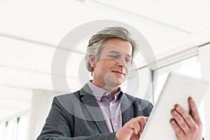 Mature businessman using tablet computer in new office