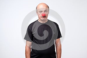 Mature businessman wearing clown nose isolated on white background