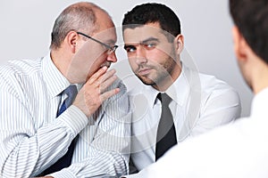 Mature businessman whisper something to colleague photo