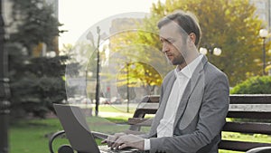 Mature businessman working on his laptop outdoors in city park