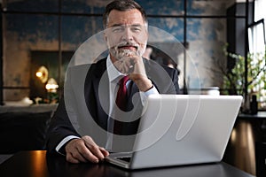 Mature businessman working on laptop. Handsome mature business leader sitting in a modern office