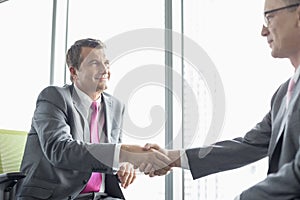 Mature businessmen shaking hands in office