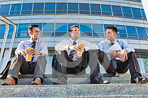 Mature businessmen sitting on stairs against office building after work