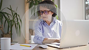 Mature businesswoman in blue shirt and glasses