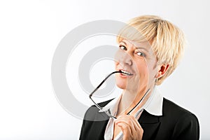 Mature businesswoman with eyeglasses earpiece in mouth