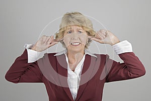 Mature businesswoman with fingers in ears