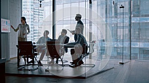 Mature businesswoman giving presentation to male colleagues in modern office