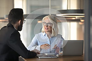 Mature businesswoman talking with business partner in office