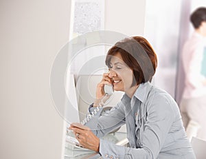 Mature businesswoman talking on landline phone