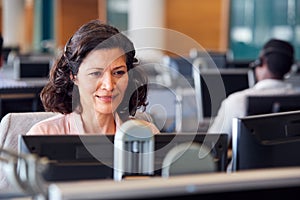 Mature Businesswoman Wearing Telephone Headset Talking To Caller In Customer Services Department