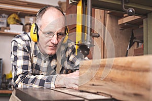 A mature carpenter using a bandsaw