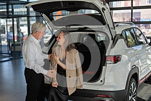 Mature Caucasian couple choosing a car looks at the trunk.