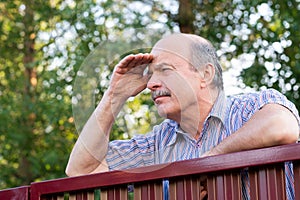 Mature caucasian man carefully watching over the fence.