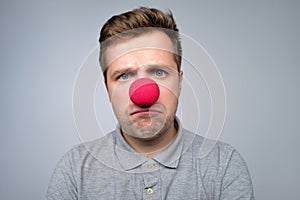 Mature caucasian man wearing clown red nose isolated on gray background