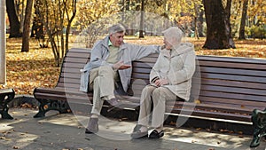 Mature caucasian older strangers couple sit on bench retired senior man arrange meeting with grey haired pretty middle