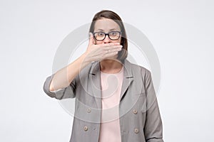 Mature caucasian woman in glasses covering mouth. I will not tell this secret anybody