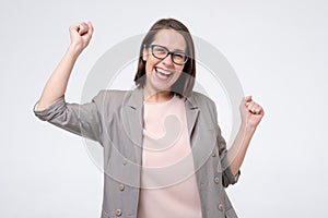 Mature caucasian woman in glasses doing a winner gesture raising fists up