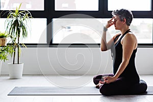 Mature Caucasian woman practicing yoga on livingroom floor