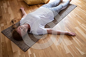 Mature caucasian woman resting after yoga practice in savasana