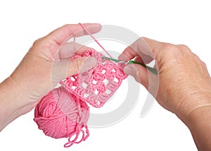 hands crocheting granny square with pink yarn, isolated