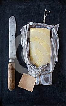 Mature cheddar cheese wrapped in rustic paper and a vintage knife.