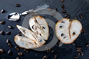 Mature cherimoyas. Open fruit, with nuggets and spoon on dark background