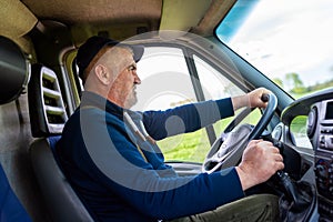 Mature confident truck driver is looking carefully at the road