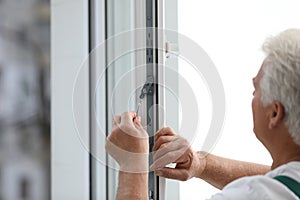 Mature construction worker repairing plastic window, closeup