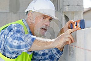 Mature construction worker using level