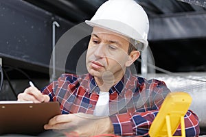 Mature contractor writing on clipboard