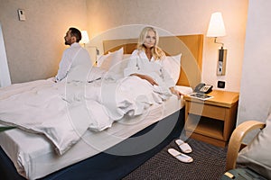 mature couple in bathrobes sitting on bed