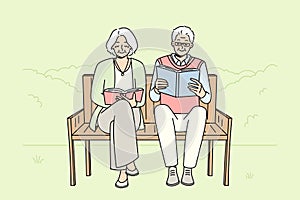 Mature couple on bench reading books