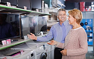 Mature couple buy in shop of household appliances TV