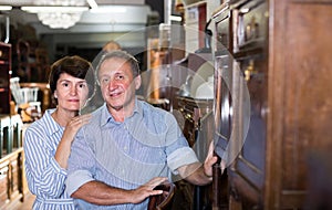 Mature couple is buying antique cupboard