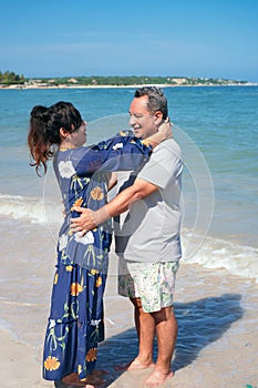 Mature couple calm and relax hugging each other standing at the beach during summer