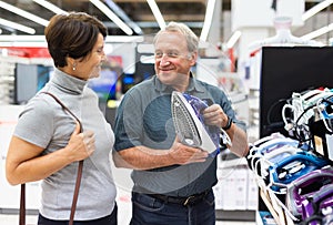 Mature couple choosing new clothes iron in electronic department hypermarket