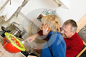 Mature couple cooking dishes in kitchen
