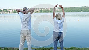 A mature couple doing yoga, raising their hands up. Connection, harmony, love and relationships