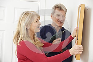 Mature Couple Drilling Wall To Hang Picture Frame