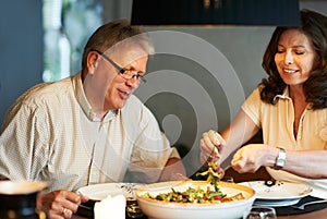 Mature couple, eating together at table with food and love in marriage with happiness in home. Lunch, old man and woman