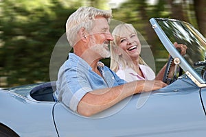 Mature Couple Enjoying Road Trip In Classic Open Top Sports Car Together