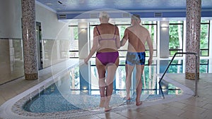 Mature couple entering hotel pool to swim