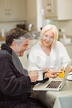 Mature couple having breakfast together man using laptop