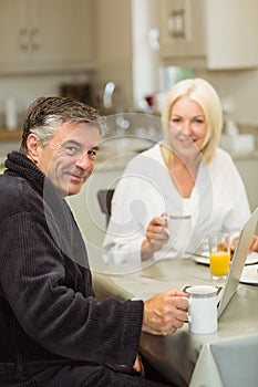 Mature couple having breakfast together man using laptop