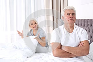 Mature couple having conflict in bedroom at home.