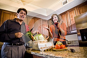 Mature couple having fun cooking in kitchen