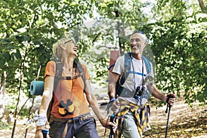 MAture couple hiking in forest wearing backpacks and hiking poles. Nordic walking, trekking. Healthy lifestyle