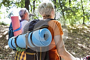 Mature couple hiking in forest wearing backpacks and hiking poles. Nordic walking, trekking. Healthy lifestyle