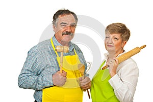 Mature couple holding kitchen utensils